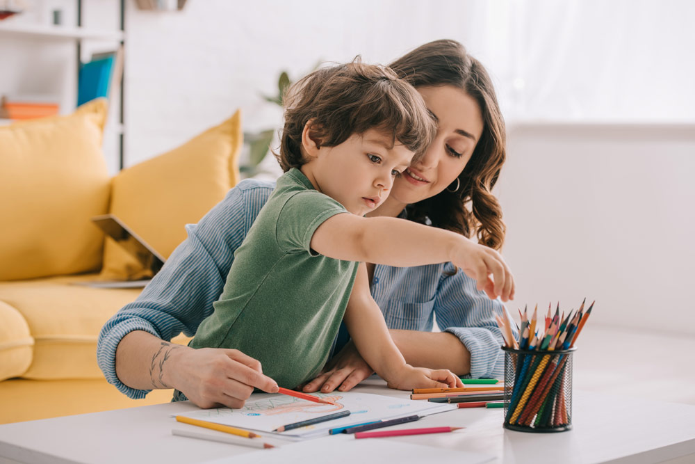 Child coloring with early childhood caregiver