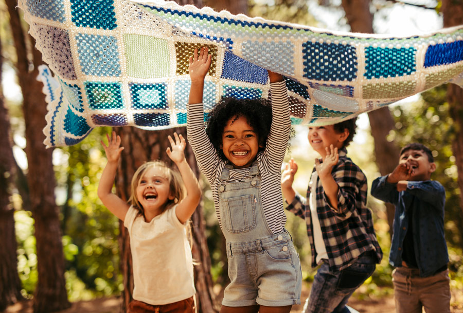 Children playing outside with blanket