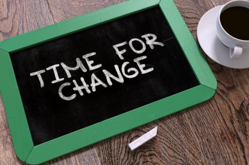 Chalkboard with "Time for Change" written on it and a cup of coffee on a table.